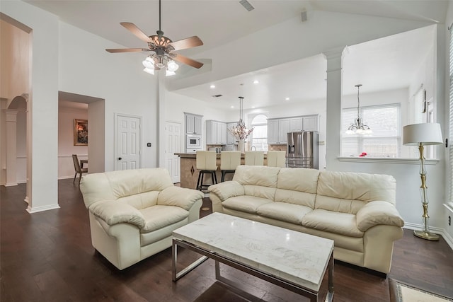 living room featuring ornate columns, plenty of natural light, dark hardwood / wood-style floors, and ceiling fan with notable chandelier