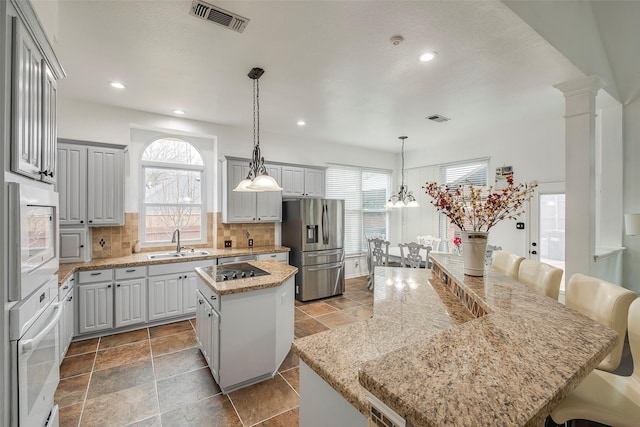 kitchen featuring sink, white oven, gray cabinetry, a center island, and stainless steel fridge with ice dispenser