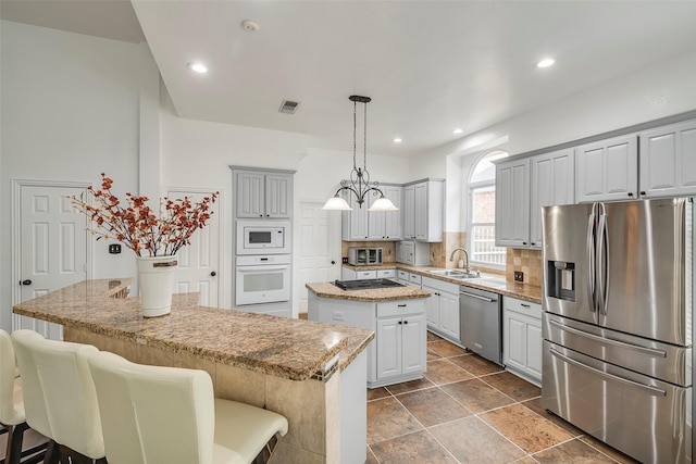 kitchen featuring appliances with stainless steel finishes, sink, backsplash, hanging light fixtures, and a center island