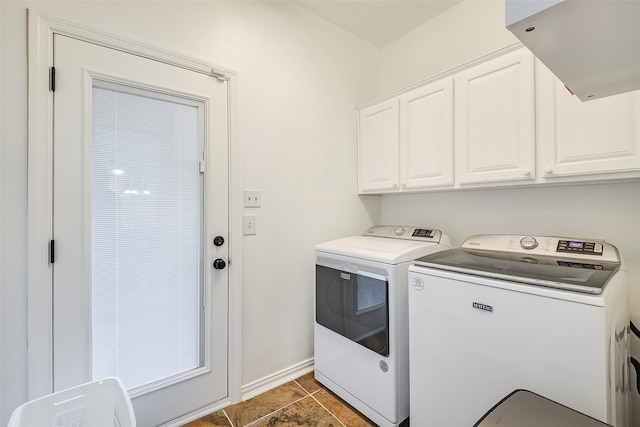 clothes washing area with cabinets, washer and clothes dryer, and dark tile patterned floors