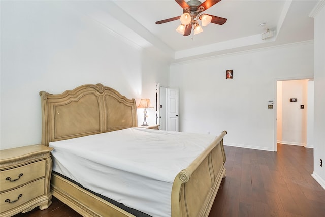 bedroom featuring dark hardwood / wood-style flooring, a tray ceiling, and ceiling fan