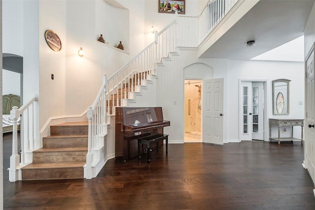 stairway with a towering ceiling and hardwood / wood-style floors