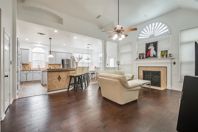 living room featuring dark wood-type flooring, lofted ceiling, a tiled fireplace, and sink