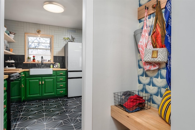 kitchen featuring sink, backsplash, white refrigerator, electric range, and green cabinetry