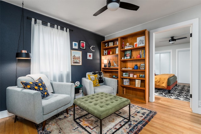 living area with wood-type flooring and ceiling fan