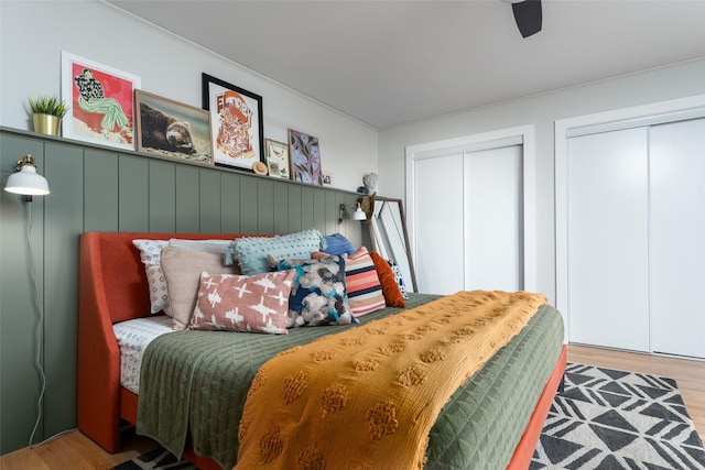 bedroom featuring hardwood / wood-style flooring, ceiling fan, and two closets