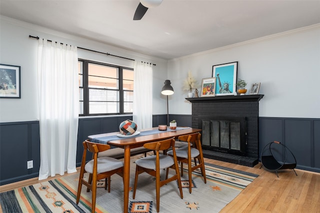 dining area with hardwood / wood-style floors, a fireplace, ornamental molding, and ceiling fan