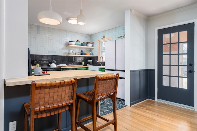 kitchen featuring black electric range oven, backsplash, white refrigerator, kitchen peninsula, and light hardwood / wood-style flooring