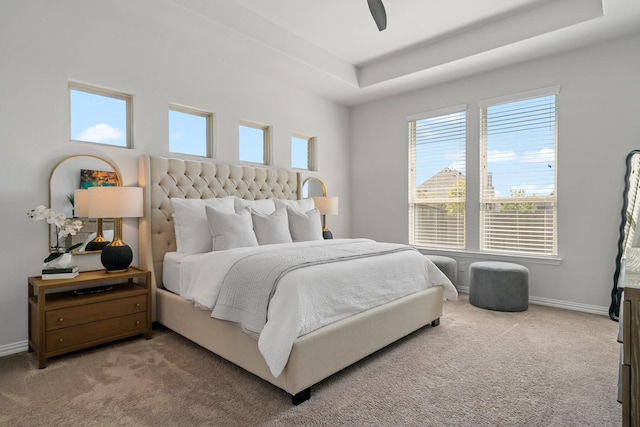 bedroom featuring a raised ceiling, carpet flooring, a ceiling fan, and baseboards