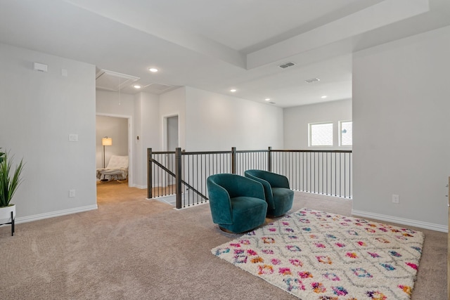 living area featuring attic access, baseboards, visible vents, and an upstairs landing