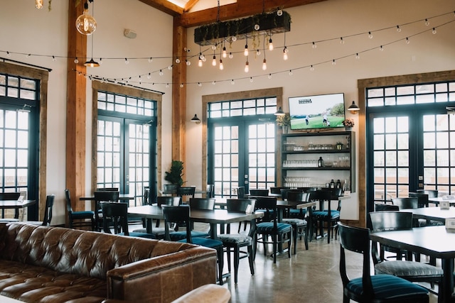 dining space with a wealth of natural light, french doors, finished concrete flooring, and a high ceiling