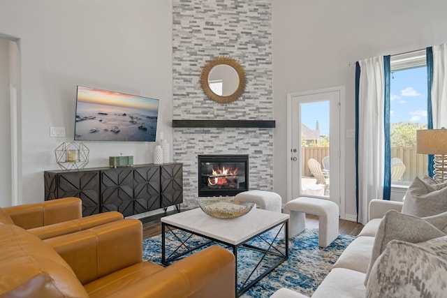 living area featuring a tile fireplace, a towering ceiling, and wood finished floors