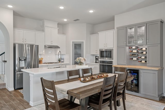 kitchen with wine cooler, stainless steel appliances, a sink, visible vents, and light countertops