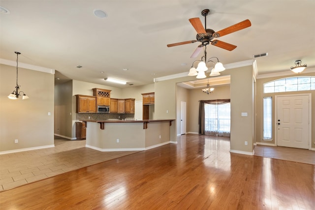 unfurnished living room with crown molding, wood-type flooring, and ceiling fan with notable chandelier