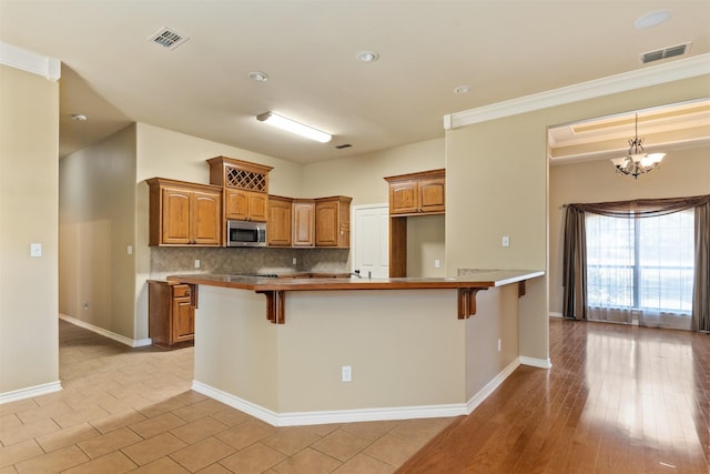 kitchen featuring tasteful backsplash, kitchen peninsula, an inviting chandelier, and a breakfast bar area