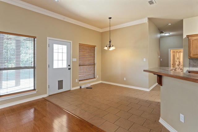 foyer entrance featuring ornamental molding, a chandelier, and light hardwood / wood-style flooring