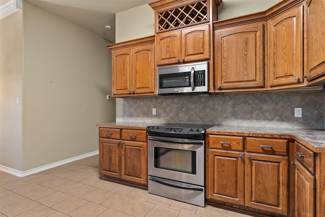 kitchen with stainless steel appliances, light tile patterned floors, and decorative backsplash