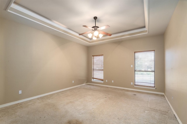 spare room featuring ceiling fan, a healthy amount of sunlight, a tray ceiling, and light carpet