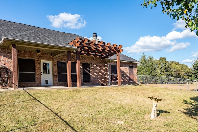 back of property featuring ceiling fan, a yard, and a pergola