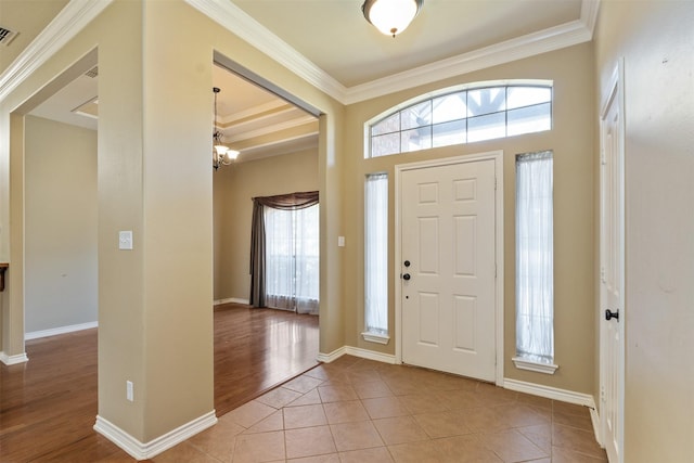 tiled entryway featuring crown molding and an inviting chandelier