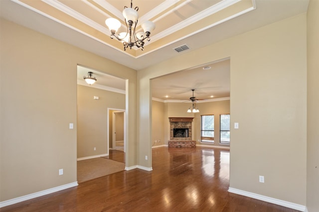 unfurnished living room with ornamental molding, wood-type flooring, a raised ceiling, and ceiling fan with notable chandelier