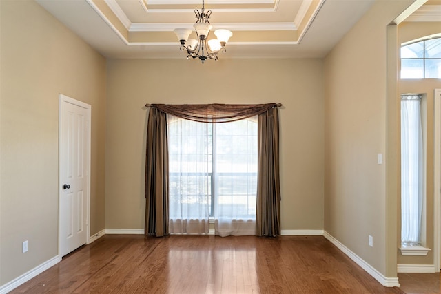 unfurnished room featuring an inviting chandelier, hardwood / wood-style flooring, ornamental molding, and a raised ceiling