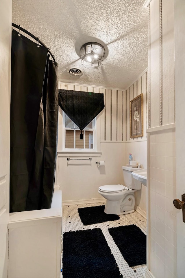 bathroom featuring a textured ceiling, tile patterned floors, toilet, and a shower with shower curtain