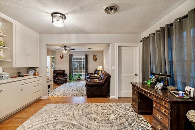 interior space with ceiling fan, light hardwood / wood-style floors, and a textured ceiling