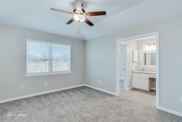 unfurnished bedroom with sink, ensuite bath, ceiling fan, light carpet, and vaulted ceiling