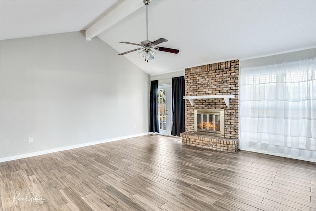 unfurnished living room featuring a fireplace, light hardwood / wood-style floors, lofted ceiling with beams, and ceiling fan