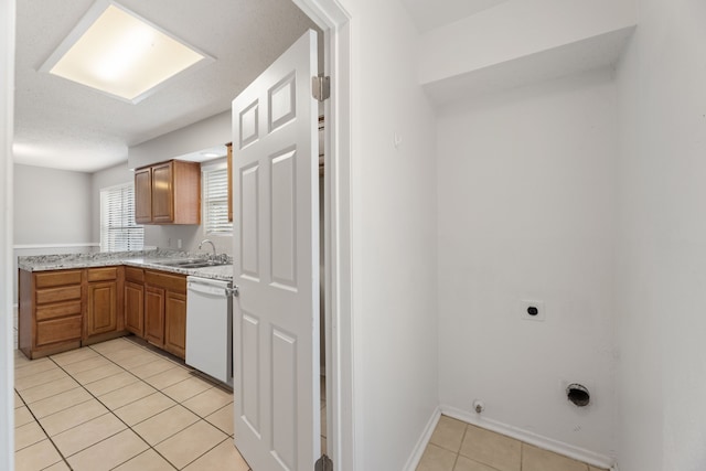 kitchen featuring light tile patterned flooring, white dishwasher, and sink