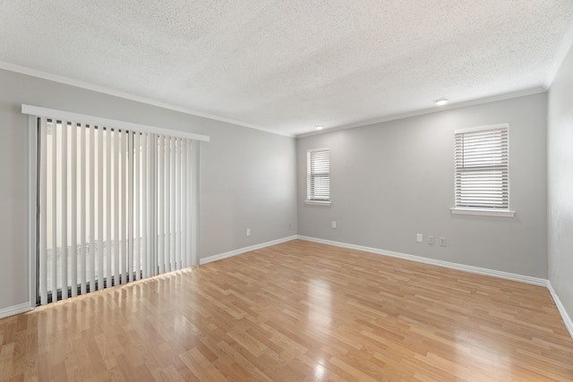 empty room featuring ornamental molding, light hardwood / wood-style floors, and a textured ceiling