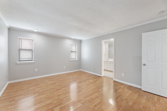 spare room featuring ornamental molding, a textured ceiling, and light wood-type flooring