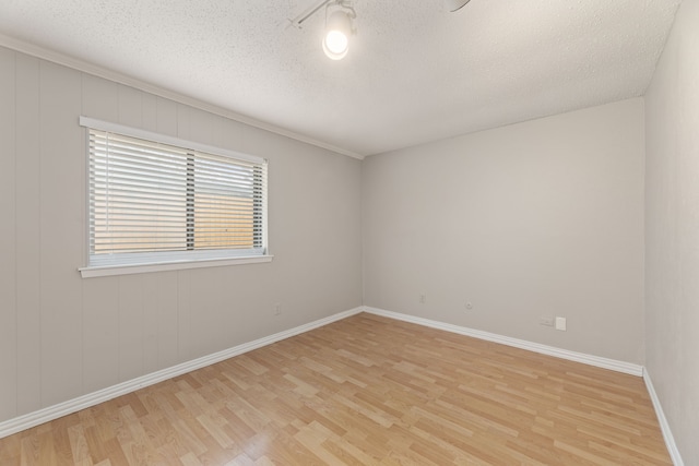 empty room with a textured ceiling and light hardwood / wood-style flooring