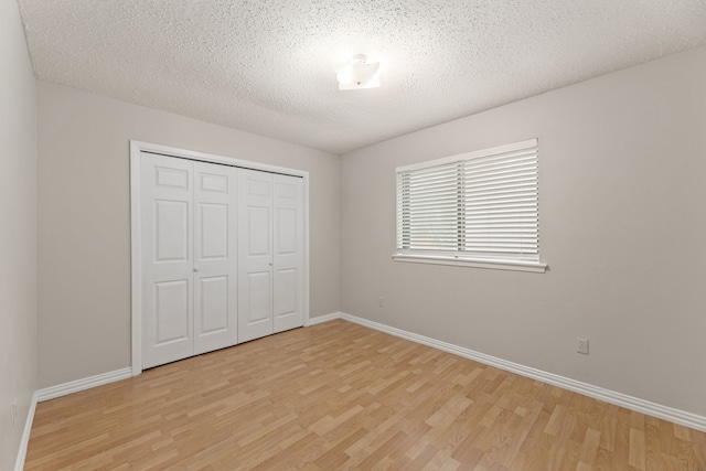 unfurnished bedroom featuring a closet, a textured ceiling, and light hardwood / wood-style flooring