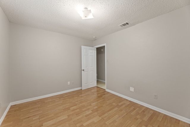 unfurnished room with a textured ceiling and light wood-type flooring