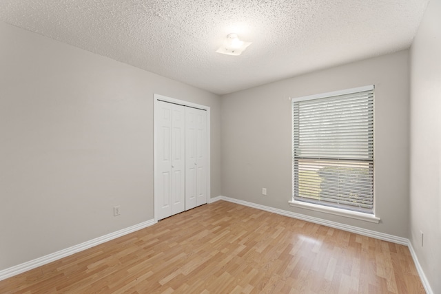 unfurnished bedroom featuring light hardwood / wood-style floors, a closet, and a textured ceiling