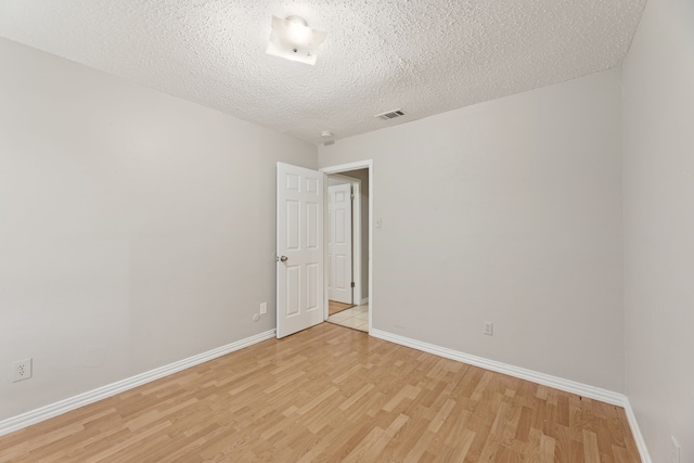 empty room with light hardwood / wood-style floors and a textured ceiling