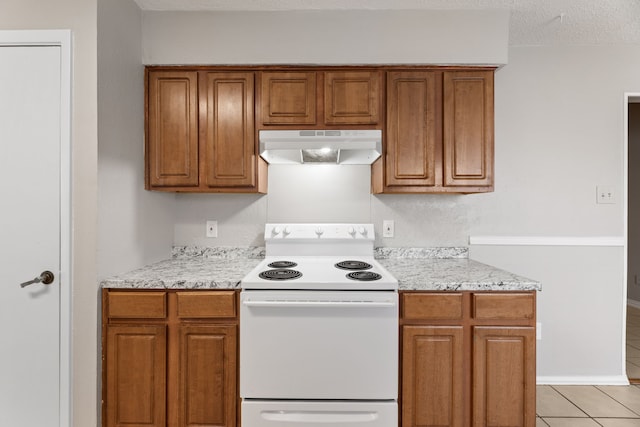 kitchen featuring light stone counters, light tile patterned flooring, a textured ceiling, and white range with electric stovetop