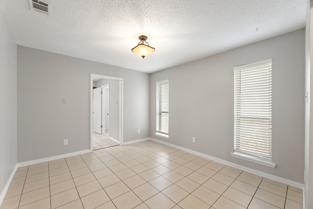 tiled spare room with plenty of natural light and a textured ceiling