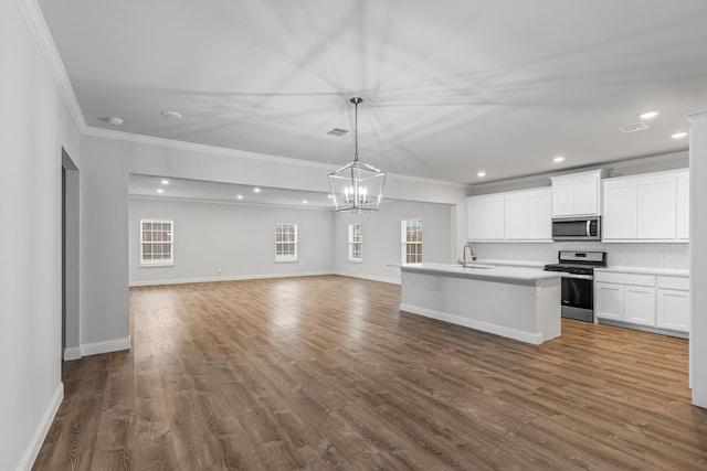 kitchen featuring sink, appliances with stainless steel finishes, white cabinetry, a center island with sink, and decorative light fixtures