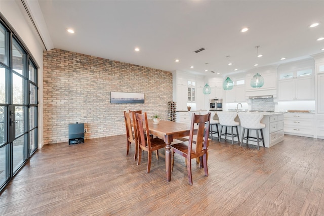 dining room with hardwood / wood-style flooring and brick wall