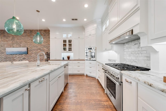 kitchen with sink, white cabinetry, pendant lighting, stainless steel appliances, and light stone countertops