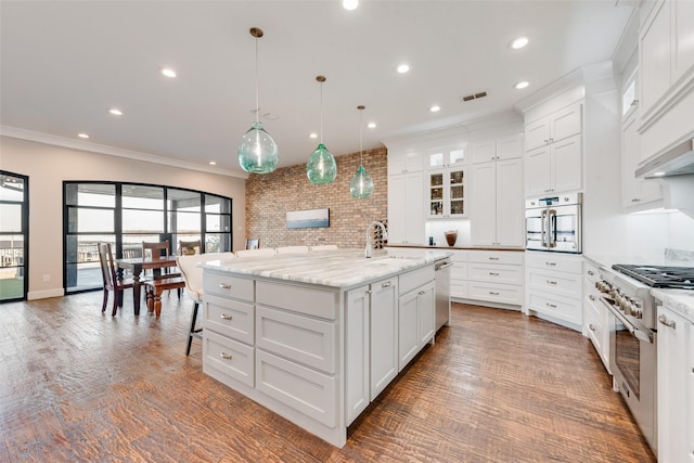 kitchen with stainless steel appliances, white cabinetry, a large island with sink, and decorative light fixtures