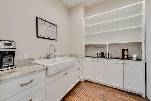 kitchen featuring light stone counters, dark wood-type flooring, sink, and white cabinets