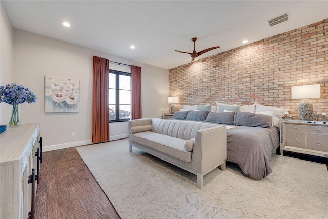 bedroom featuring light hardwood / wood-style floors, ceiling fan, and brick wall