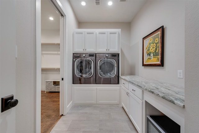 washroom with washer and dryer and cabinets