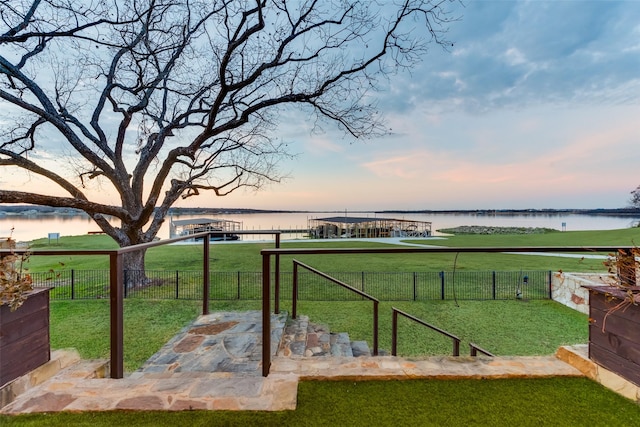 yard at dusk featuring a water view