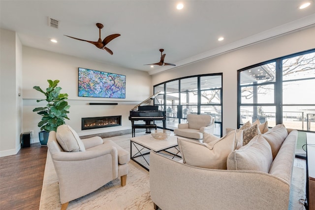 living room featuring wood-type flooring, plenty of natural light, and ceiling fan