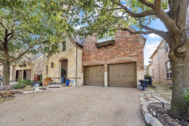 view of front facade with an attached garage, stone siding, concrete driveway, and brick siding